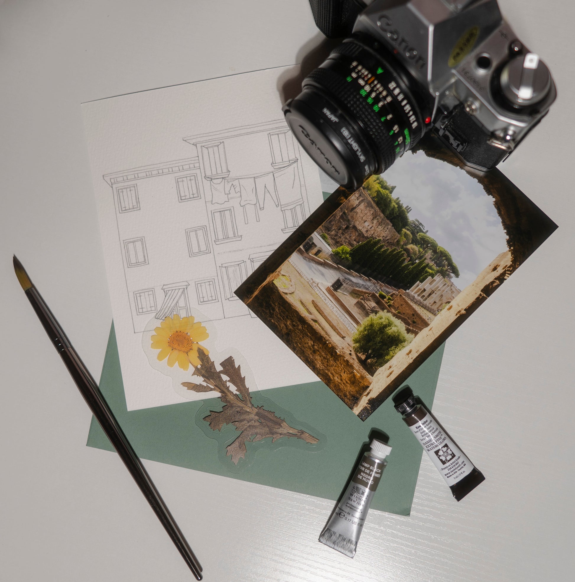 Camera, drawing, painting supplies on a white surface